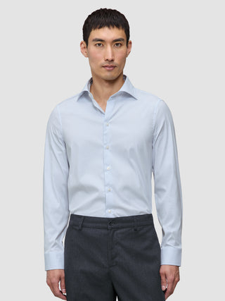 En man klädd i en Elevated-skjorta i modell Regular Classic med blå ränder och grå byxor.
