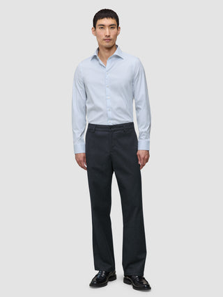 En man bär en blå randig skjorta av märket Elevated Shirt Regular Classic, instoppad i mörkgrå byxor och svarta loafers.
