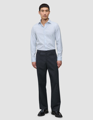 En man bär en blå randig skjorta av märket Elevated Shirt Regular Classic, instoppad i mörkgrå byxor och svarta loafers.