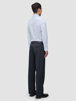 En person sedd bakifrån, klädd i en ljusblå randig Elevated Shirt Regular Classic Blue Striped och mörka byxor.