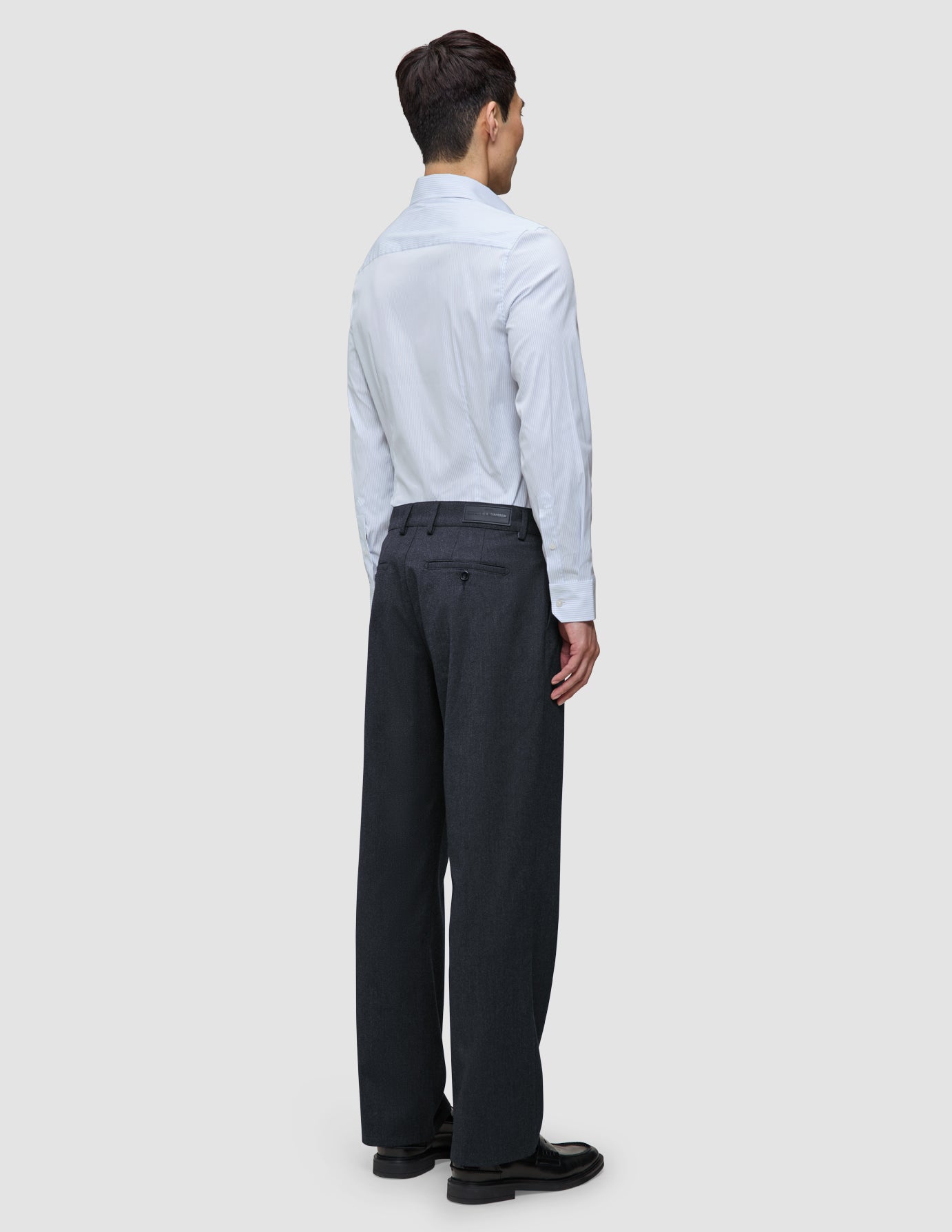 En person sedd bakifrån, klädd i en ljusblå randig Elevated Shirt Regular Classic Blue Striped och mörka byxor.