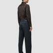 En man sedd bakifrån i en mörkbrun skjorta av modellen Elevated Shirt Regular, instoppad i kolgrå byxor och mörka loafers.