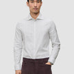 Man klädd i en slim fit-skjorta i ljusgrått med vertikala ränder och långa ärmar, modell Elevated Shirt Slim Light Grey Striped.