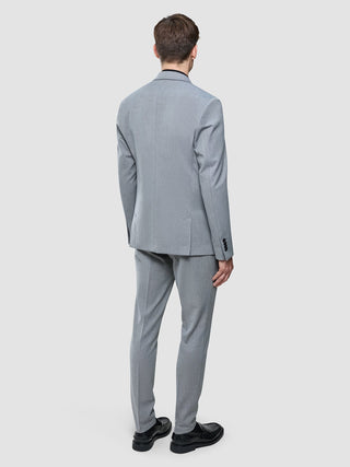 En man sedd bakifrån, klädd i en Essential Blazer Regular Ash Twill och svarta kostymskor.