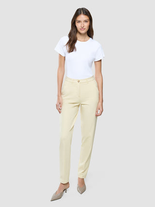 En kvinna klädd i en vit t-shirt och ett par Women Essential Pants Tapered i färgen Misty Yellow.