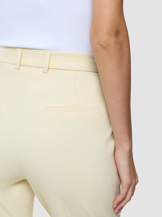 Bakifrånbild av en person som bär Women Essential Pants Tapered i färgen Misty Yellow tillsammans med en vit överdel.