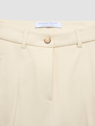 Närbild på beigea dambyxor av modellen ”Essential Pants Tapered” i färgen ”Misty Yellow” med en ”Shaping New Tomorrow”-etikett på insidan av midjebandet.