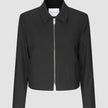 Essential Short Zip Jacket Black: en minimalistisk, kort svart jacka med en helsilverfärgad dragkedja framtill.
