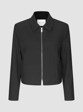 Essential Short Zip Jacket Black: en minimalistisk, kort svart jacka med en helsilverfärgad dragkedja framtill.