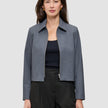 En kvinna som bär en mörkgrå Essential Short Zip Jacket i mörkgrå melange över en svart topp.