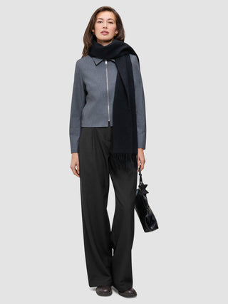 En person klädd i en Essential Short Zip Jacket i mörkgrå melange, en svart halsduk, byxor med vida ben och en svart handväska.
