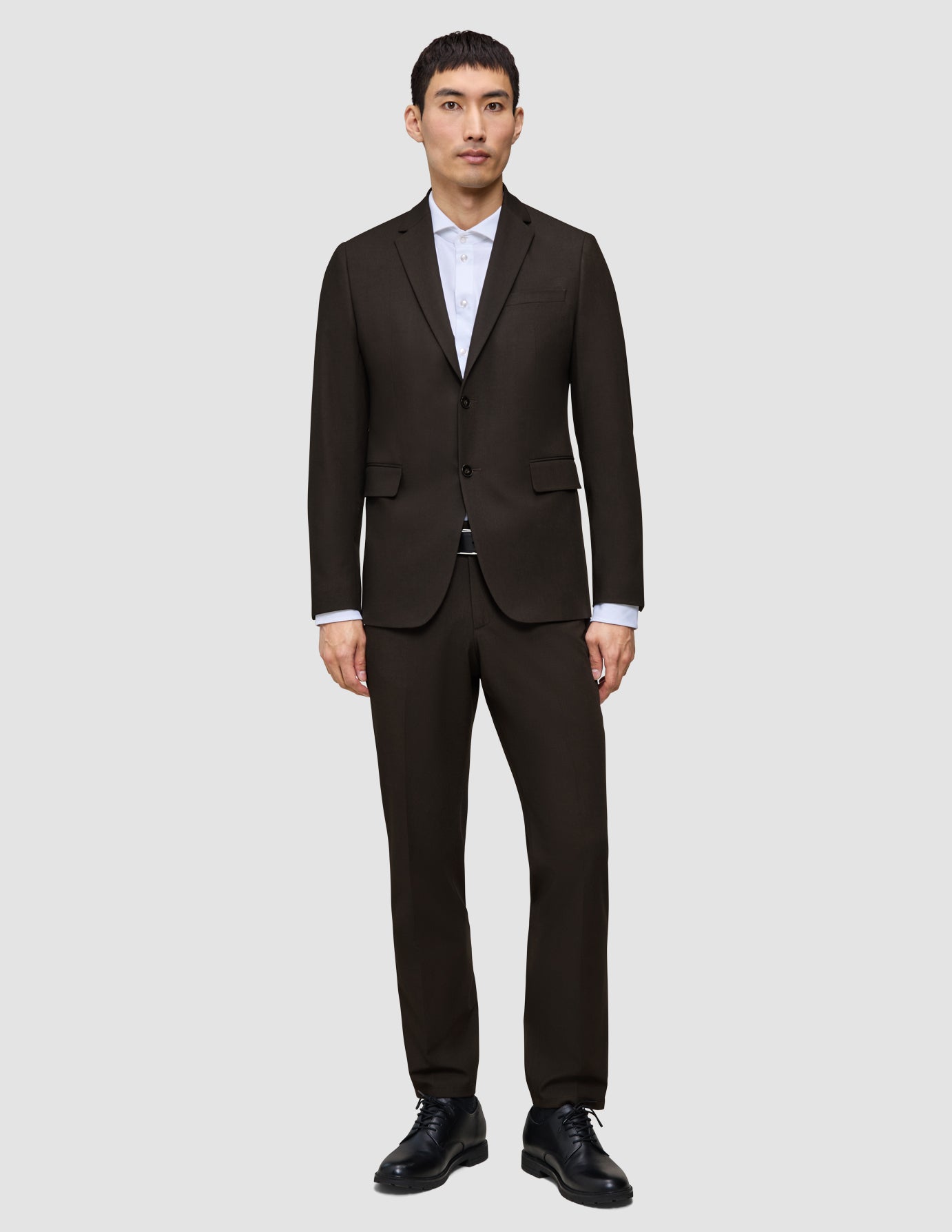 En man bär en Motion Blazer Regular i färgen Cognac över en vit skjorta med krage och svarta kostymskor.