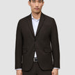 En man klädd i en mörkbrun Motion Blazer Slim Cognac över en vit skjorta.