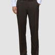 En person bär byxor av modellen Motion Suit Pants Relaxed Cognac, en vit skjorta med knappar och mörka läderskor av typen loafers.