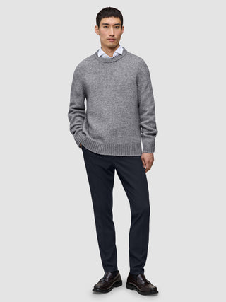 En man i en grå tröja, en vit skjorta med krage och midnattsblå Motion Suit Pants Slim samt loafers.