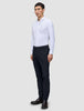 En man klädd i en vit skjorta, ett par slim fit-byxor av modellen Motion Suit Pants Slim i midnattsblått och mörka läderskor.