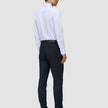 En person sedd bakifrån, klädd i en vit skjorta, Motion Suit-byxor i modell Slim i färgen Midnight Blue och mörka loafers.
