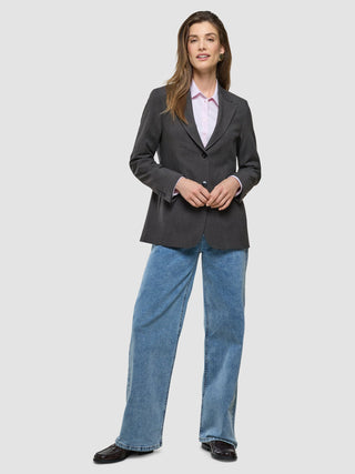 En kvinna som bär en Women Nara Blazer Cool Brown över en rosa skjorta med krage och blå jeans.