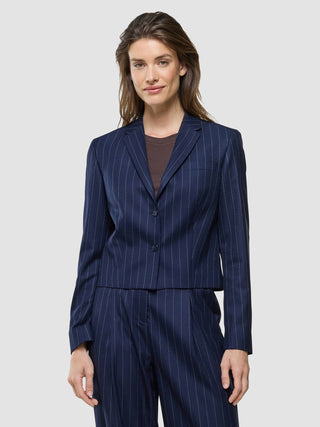 En kvinna som bär en ”Women Raina Short Blazer Night Sky Pinstripe” över en brun topp.