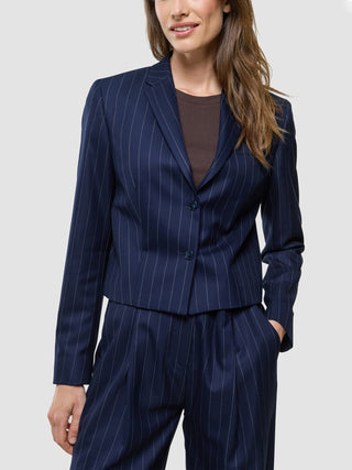En kvinna klädd i en ”Women Raina Short Blazer Night Sky Pinstripe” och matchande byxor.