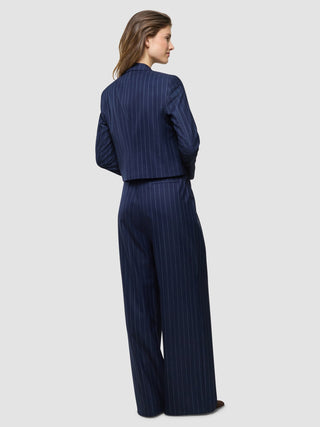 En kvinna sedd bakifrån, klädd i en Women Raina Short Blazer Night Sky Pinstripe och matchande byxor med vida ben.