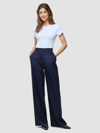 En kvinna bär en vit t-shirt som är instoppad i ett par Women Raina Pants Wide Night Sky Pinstripe.