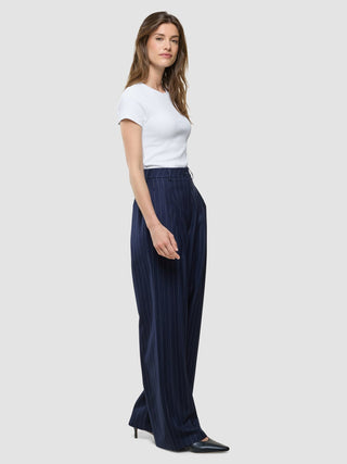 En kvinna klädd i en vit t-shirt och ett par Women Raina Pants Wide Night Sky Pinstripe.