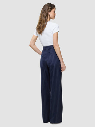 En kvinna sedd bakifrån, klädd i en vit t-shirt och ett par Women Raina Pants Wide Night Sky Pinstripe.