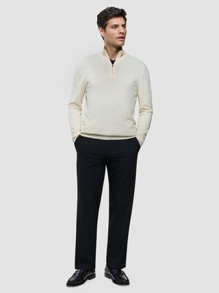 En man bär en Seamless Core Knit Half Zip Birchwood-tröja tillsammans med svarta byxor och svarta loafers.