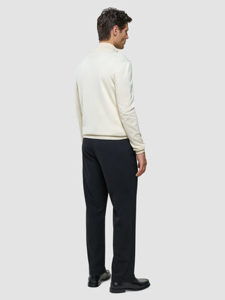 En man sedd bakifrån, klädd i en Seamless Core Knit Half Zip Birchwood och mörka byxor.