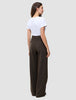 Kvinna i en vit t-shirt och mörkbruna, högmidjade, randiga byxor med vida ben av modellen Serene Pants Wide Walnut Herringbone.