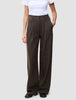 En person som bär ett par bruna Serene Pants Wide Walnut Herringbone-byxor med hög midja och vida ben, tillsammans med en vit t-shirt.