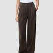 En person som bär ett par bruna Serene Pants Wide Walnut Herringbone-byxor med hög midja och vida ben, tillsammans med en vit t-shirt.