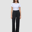 En kvinna klädd i en vit t-shirt och svarta, vidbyxor av modellen Serene Pants Wide Black.