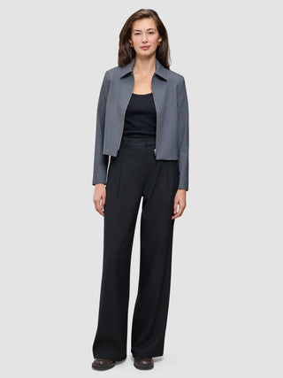 En person i en grå jacka med krage och en svart överdel bär ett par högmidjade Serene Pants Wide Black.