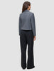 En person sedd bakifrån, klädd i en grå kavaj och svarta Serene Pants Wide Black med hög midja.