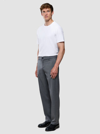 En man klädd i en vit t-shirt och ett par Siena-byxor i avslappnad passform med fiskbensmönster i grått.