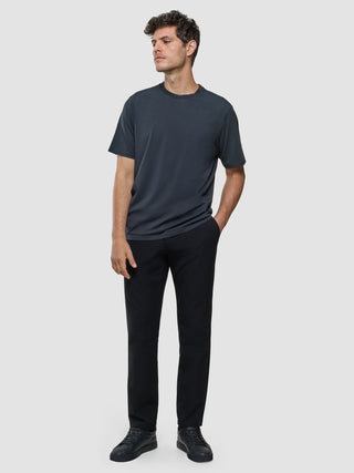En man klädd i en Supima-T-shirt i modell Box Fit i färgen Deep Grey, svarta byxor och svarta sneakers med skandinavisk design.