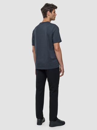 En man sedd bakifrån, klädd i en Supima-T-shirt i modell ”Box Fit” i färgen ”Deep Grey”, svarta byxor och svarta sneakers med 360°-stretch.