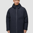 En man klädd i en svart, knälång Utility Jacket Black med huva.
