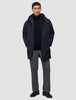 En man bär en svart Utility Jacket över en svart tröja med kvartslås och grå byxor.