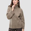 En kvinna klädd i en tjock, mjuk ullstickad turtleneck-tröja i färgen taupe melange från kollektionen Women.