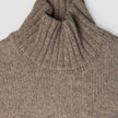 Dammåttig, tjock och mjuk ulltröja med hög hals i taupe-melange och ribbad struktur.