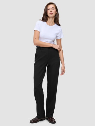 En kvinna klädd i en vit t-shirt, Women GO2 Pants Straight Black och mörka loafers i en ren skandinavisk design.