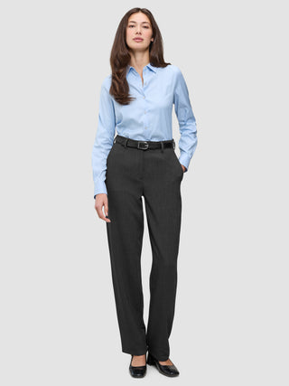 En kvinna klädd i en ljusblå skjorta med knappar, ett svart bälte och byxor av modellen Women GO2 Pants Straight i mörkgrå melange.