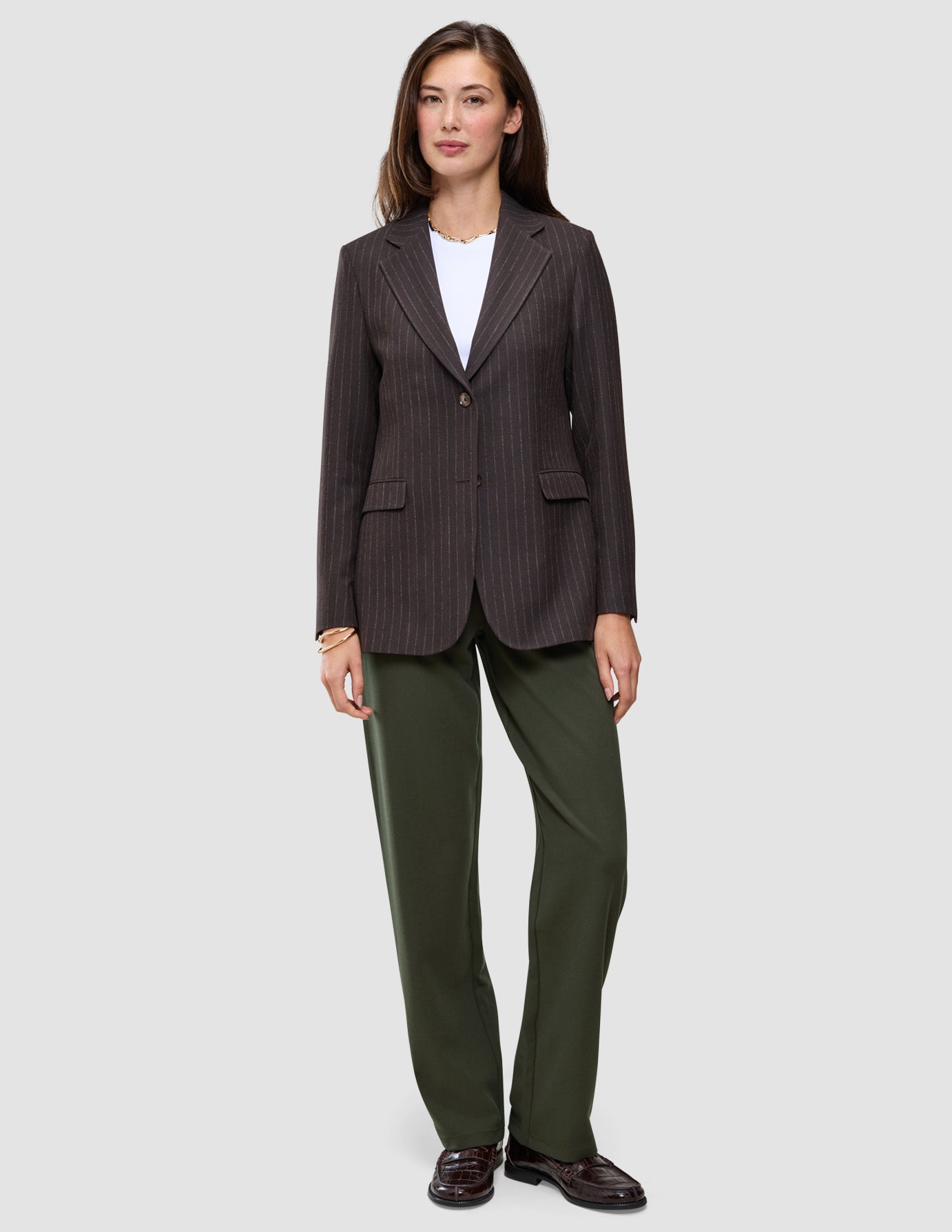 En mörkbrun blazer med smala ränder över en vit t-shirt, i kombination med Women GO2 Pants Straight Dusty Olive i klassisk design.