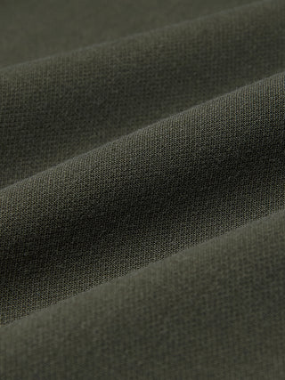 Närbild på olivgröna GO2-byxor för damer i rakt snitt, i tyget Dusty Olive med mjuka veck, som präglas av en minimalistisk design.