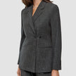 En kvinna bär en Women Nara Blazer Fitted Black Check, en skräddarsydd, svart- och vitrutig blazer med dubbelknäppning.