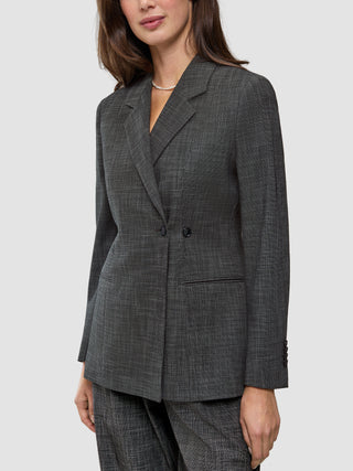 En kvinna bär en Women Nara Blazer Fitted Black Check, en skräddarsydd, svart- och vitrutig blazer med dubbelknäppning.