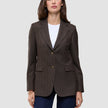En kvinna bär en brun, valnötsfärgad Women Serene Blazer Regular i fiskbensmönster över en vit t-shirt och mörkblå jeans.